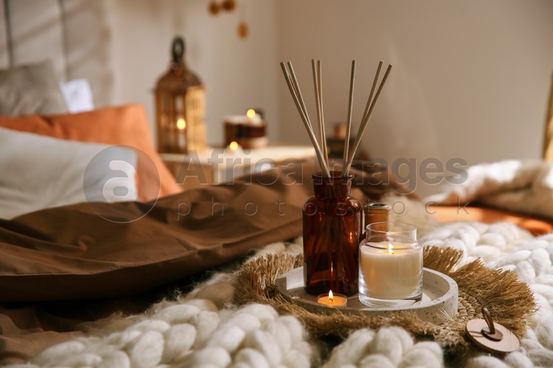 Photo of Air reed freshener and burning candles on bed indoors, space for text. Interior elements