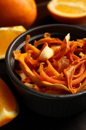 Photo of Bowl with dry orange peels and fresh fruits on table, closeup