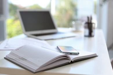 Planner and modern smartphone on table in office