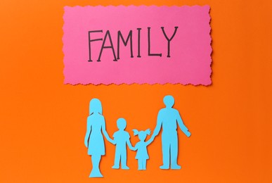 Card with text Family and paper cutout on orange background, flat lay