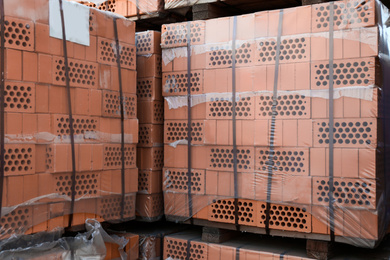 Photo of Pallets with red bricks outdoors. Building materials wholesale