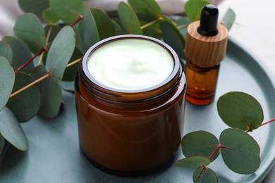 Different hand care cosmetic products and eucalyptus branches on table, closeup