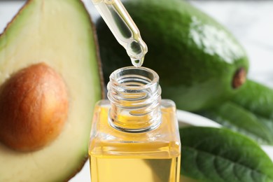 Dripping avocado essential oil into bottle, closeup