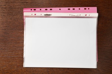 Photo of File folder with punched pockets on wooden table, top view. Space for text