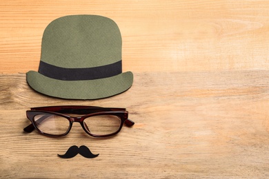 Flat lay composition with glasses, paper hat and mustaches on wooden background. Father's day celebration