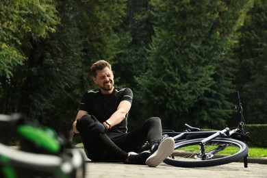 Photo of Man with injured knee near bicycle outdoors