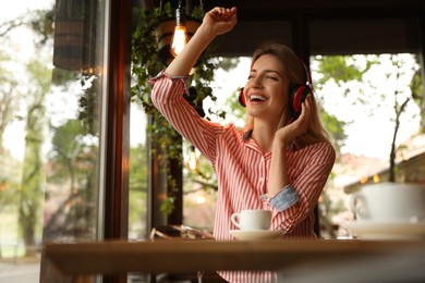 Young woman with headphones listening to music in cafe