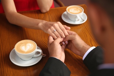 Man with engagement ring making proposal to his girlfriend in cafe, closeup