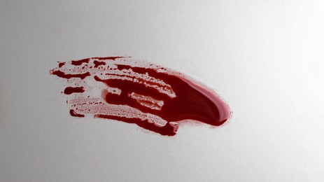 Stain of blood on grey background, top view