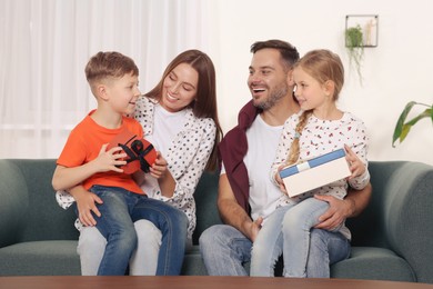 Happy family presenting each other with gifts on sofa at home