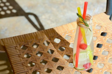 Photo of Refreshing tasty lemonade served in glass bottle on wicker surface. Space for text