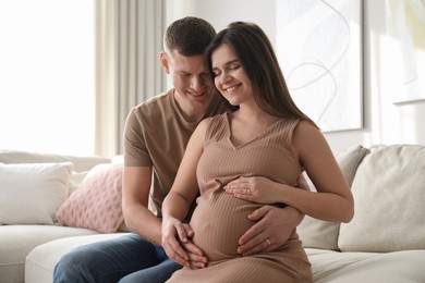 Man touching his pregnant wife's belly at home