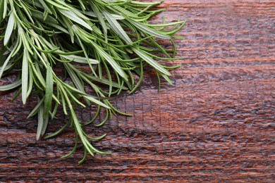Fresh green rosemary twigs on wooden table, closeup. Space for text