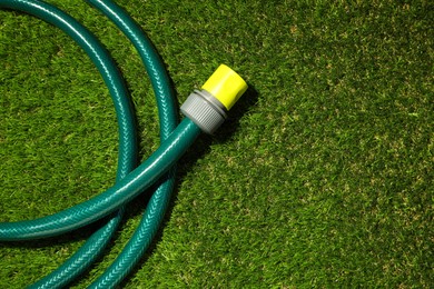 Watering hose on green grass, top view. Space for text