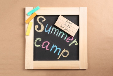 Composition with block calendar and words SUMMER CAMP written on small blackboard, top view