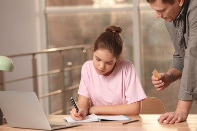 Father talking with his teenage daughter about contraception while she doing homework at home. Sex education concept