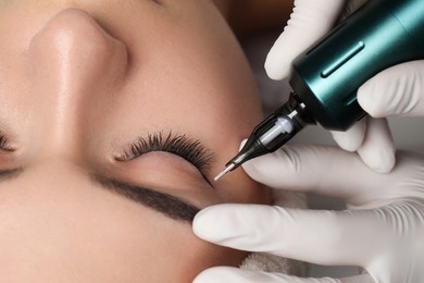 Photo of Young woman undergoing procedure of permanent eye makeup, closeup