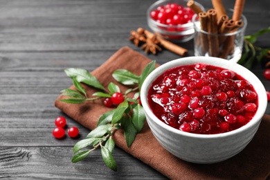 Fresh cranberry sauce served in bowl on grey wooden table, space for text