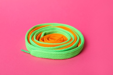 Mint and orange shoe laces on pink background