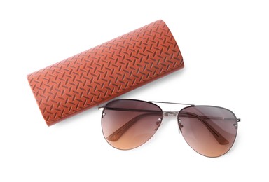 Stylish sunglasses and brown leather case on white background, top view