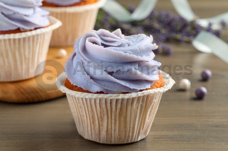 Photo of Tasty cupcake with cream on wooden table, closeup