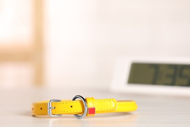 Yellow leather dog collar on table against blurred background, space for text