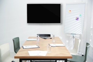 Modern wide screen TV on white wall in conference room 