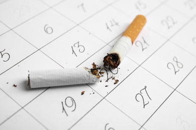 Cigarette stubs on calendar sheet. Quitting smoking concept