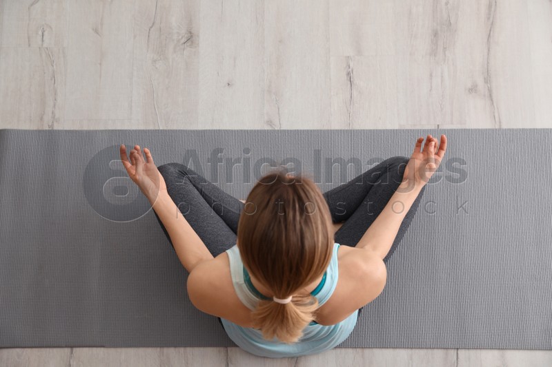 Young woman meditating indoors, top view. Zen concept