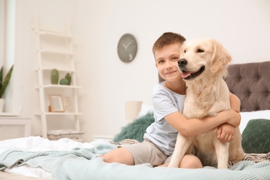 Photo of Cute little child with his pet on bed at home