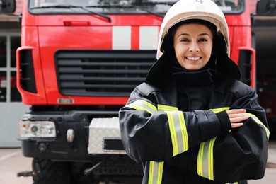 Portrait of firefighter in uniform and helmet near fire truck outdoors