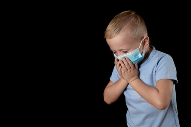 Little boy in medical mask on black background, space for text. Virus protection