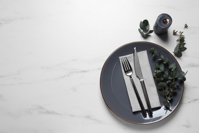Photo of Stylish setting with cutlery and eucalyptus leaves on white marble table, flat lay. Space for text