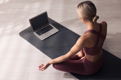 Woman watching online yoga class at home