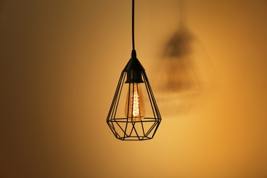 Photo of Hanging lamp bulb in chandelier against yellow background