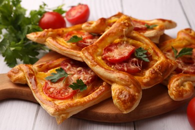 Photo of Fresh delicious puff pastry with cheese, tomatoes and parsley on white wooden table, closeup