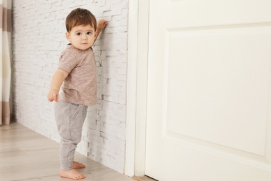 Cute baby holding on to wall at home.  Learning to walk