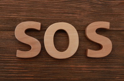 Abbreviation SOS made of letters on wooden table, top view