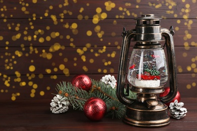 Beautiful Christmas snow globe in vintage lantern and festive decor on wooden table. Space for text