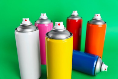 Colorful cans of spray paints on green background