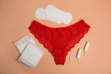 Flat lay composition with woman's underwear and menstrual pads on pale orange background. Gynecological care