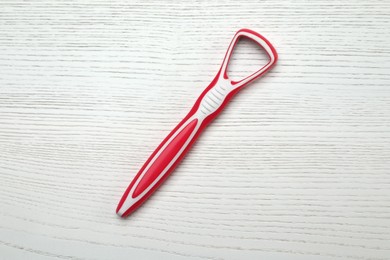 Red tongue cleaner on white wooden table, top view