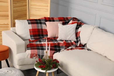 Photo of Sofa with pillows, candles and Christmas decoration on table in living room