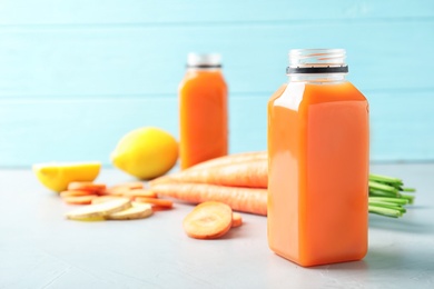 Bottles with carrot juice and fresh ingredients on table