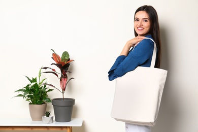 Beautiful young woman with stylish blank eco bag against color background