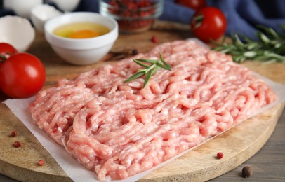 Raw chicken minced meat with rosemary on grey wooden table, closeup