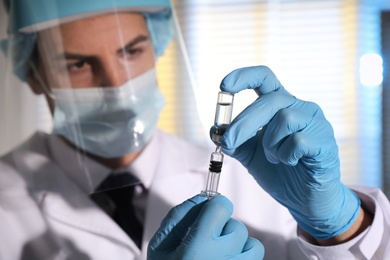 Doctor filling syringe with vaccine against Covid-19 in laboratory, focus on hands