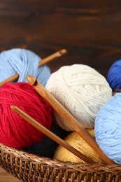 Clews of colorful knitting threads and crochet hooks in wicker basket, closeup