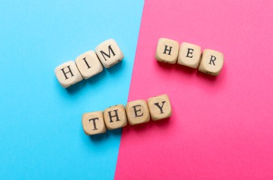 Gender pronouns made of wooden cubes on color background, flat lay