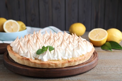 Delicious lemon meringue pie decorated with mint on wooden table